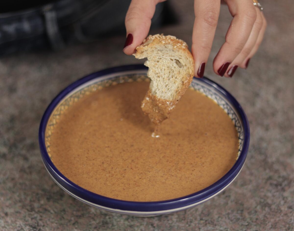 Doigts trempant du pain dans de l'amlou marocain
