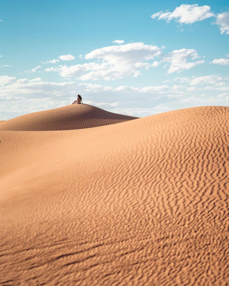 Femme assise sur une dune dans le désert au Maroc
